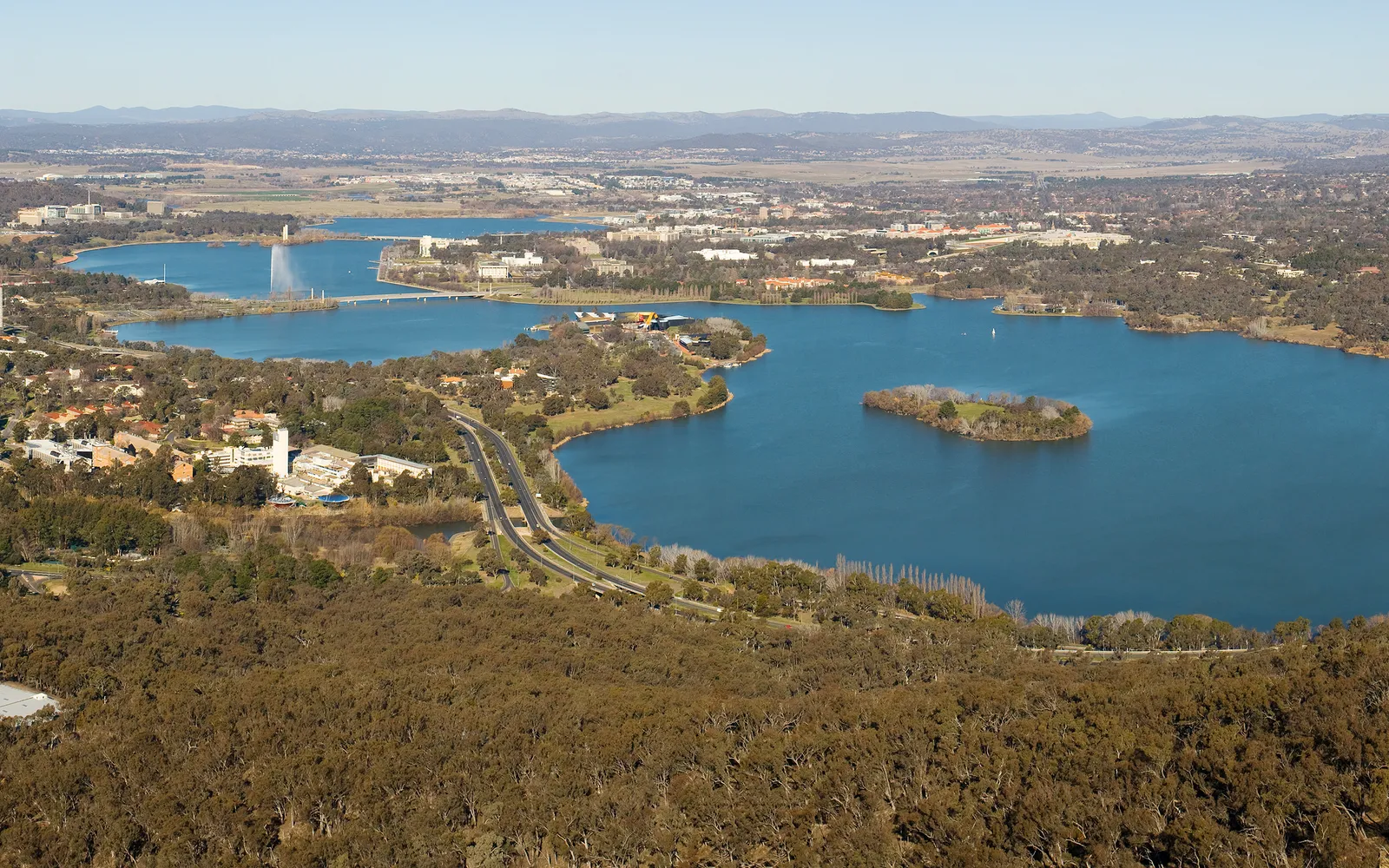 ทะเลสาบ Burley Griffin ใจกลางแคนเบอร์รา น้ำพุ Captain Cook Memorial พ่นน้ำสูงเด่น มีเรือใบและนกน้ำลอยอยู่บนน้ำสีฟ้า