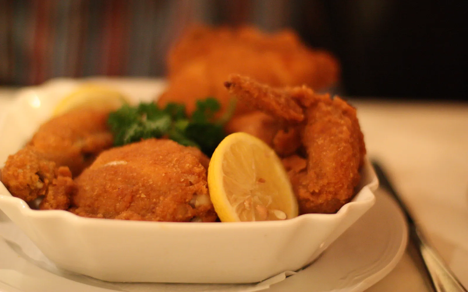 Crispy Backhendl fried chicken on a plate, coated in golden breadcrumbs, served with Erdaepfelsalat potato salad and lemon slices