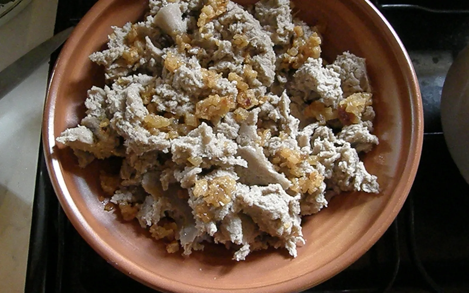 Golden Styrian Sterz cornmeal in a cast-iron pan with melting butter on top, served with sour milk, Steirische Speck and pickled vegetables