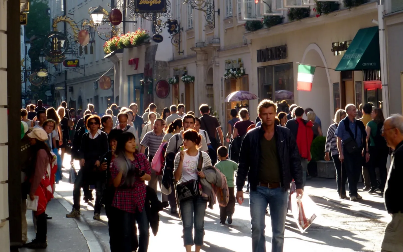 ถนน Getreidegasse ในซาลส์บวร์ก ป้ายโลหะแกะสลักทรงศิลปะของร้านค้าและร้านอาหารแขวนเรียงรายบนอาคารเก่าหลายร้อยปี