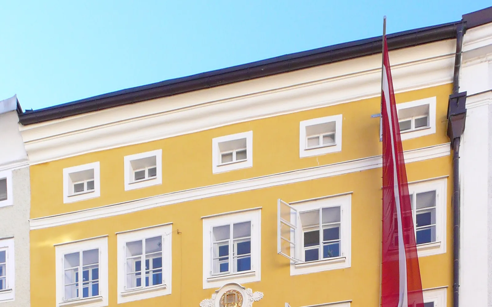 อาคารสีเหลืองสดใสที่บ้านเกิดโมซาร์ตบนถนน Getreidegasse ป้ายทองแจ้งว่า Wolfgang Amadeus Mozart เกิดที่นี่เมื่อ 27 มกราคม 1756