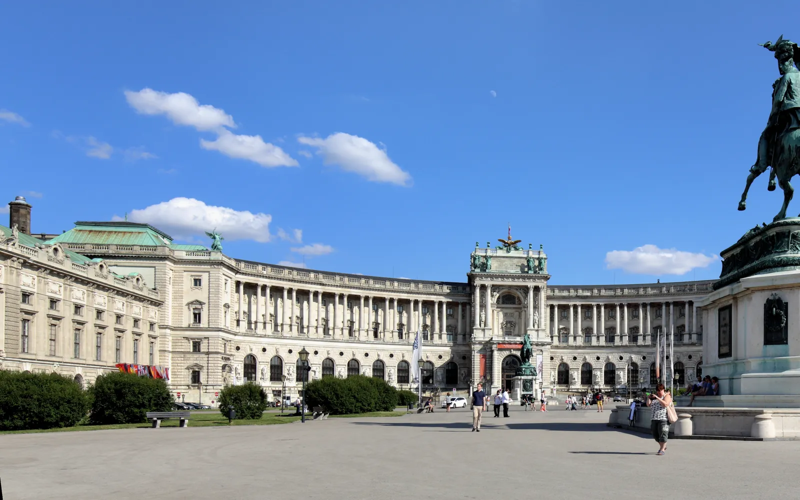 The round green dome and curved wings of the Hofburg in central Vienna, a warrior statue on the golden gateway standing tall above a granite square
