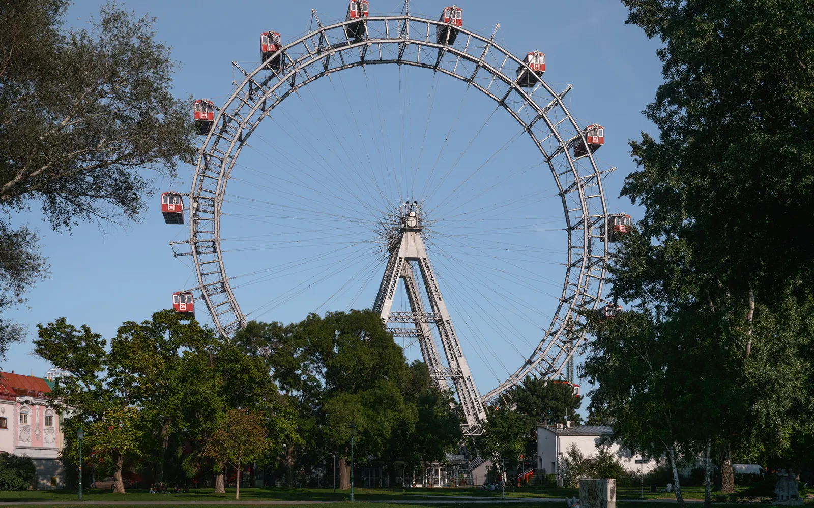 The giant bright-red Riesenrad Ferris wheel turning above Vienna's Prater park, its old wooden cabins catching the light of the setting sun