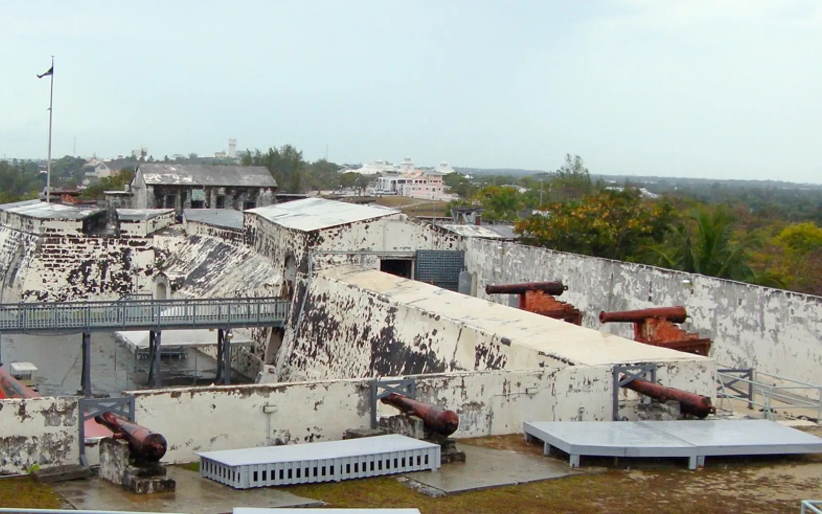 กำแพงหินและปืนใหญ่ของป้อม Fort Charlotte มองเห็นท่าเรือแนสซอด้านหลัง