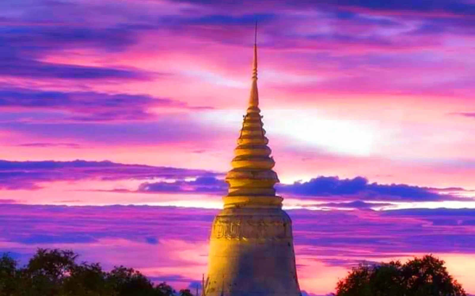 วัดพนมบนเนินดินเขียวขจี เจดีย์สีขาวผุดขึ้นเหนือต้นไม้ใหญ่ บันไดพญานาคสองข้างนำขึ้นสู่วิหาร