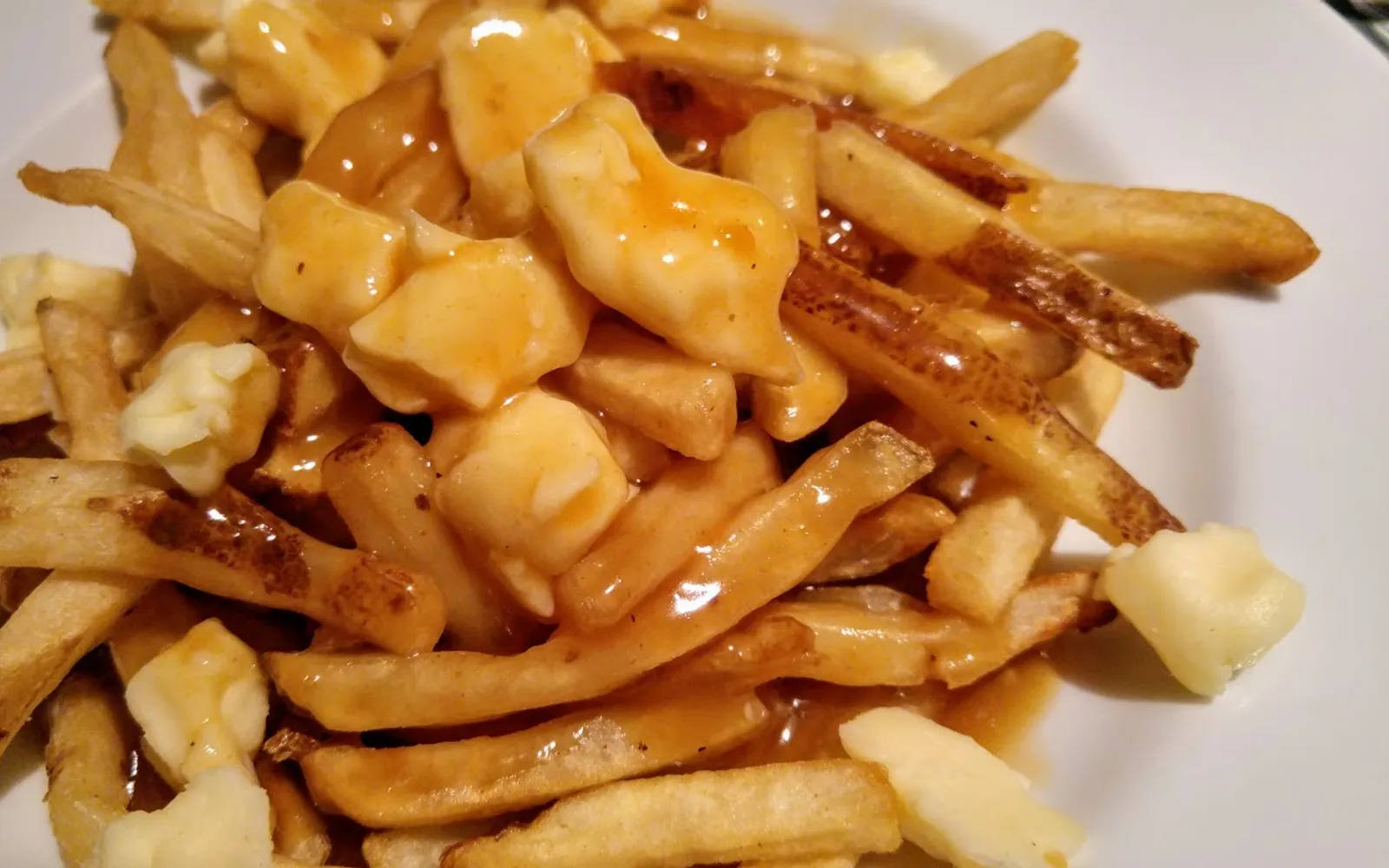 จาน Poutine มันฝรั่งทอดกรอบราดซอสน้ำเกรวีเข้มข้นและชีส Curds ละลาย