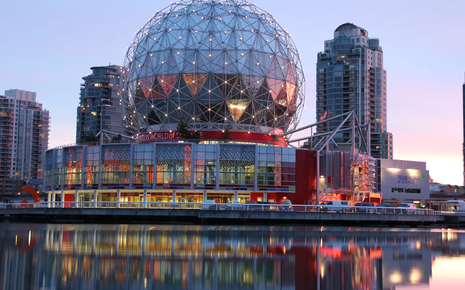 โดมทรงกลมโลหะสีเงินของ Science World สะท้อนอยู่ในน้ำ False Creek ยามเย็น