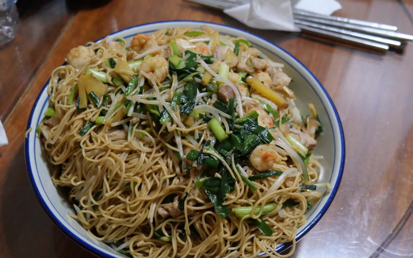 หมี่ผัดสไตล์เทียนจินในกระทะร้อน เส้นหมี่ข้าวสาลีผัดกับหมูสับ ถั่วงอก หัวหอม และซอสถั่วเหลืองดำ สีน้ำตาลเข้มมันวาว