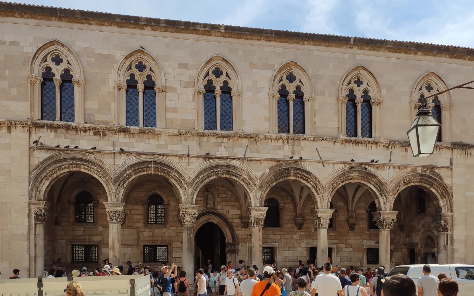 หน้าอาคาร Rector's Palace ดูบรอฟนิก เสาหินปูนโกธิก-เรเนสซองส์และโค้งประตูสูงใหญ่ตระหง่าน รูปปั้นอัศวินริเชียร์บนเสาทางซ้าย
