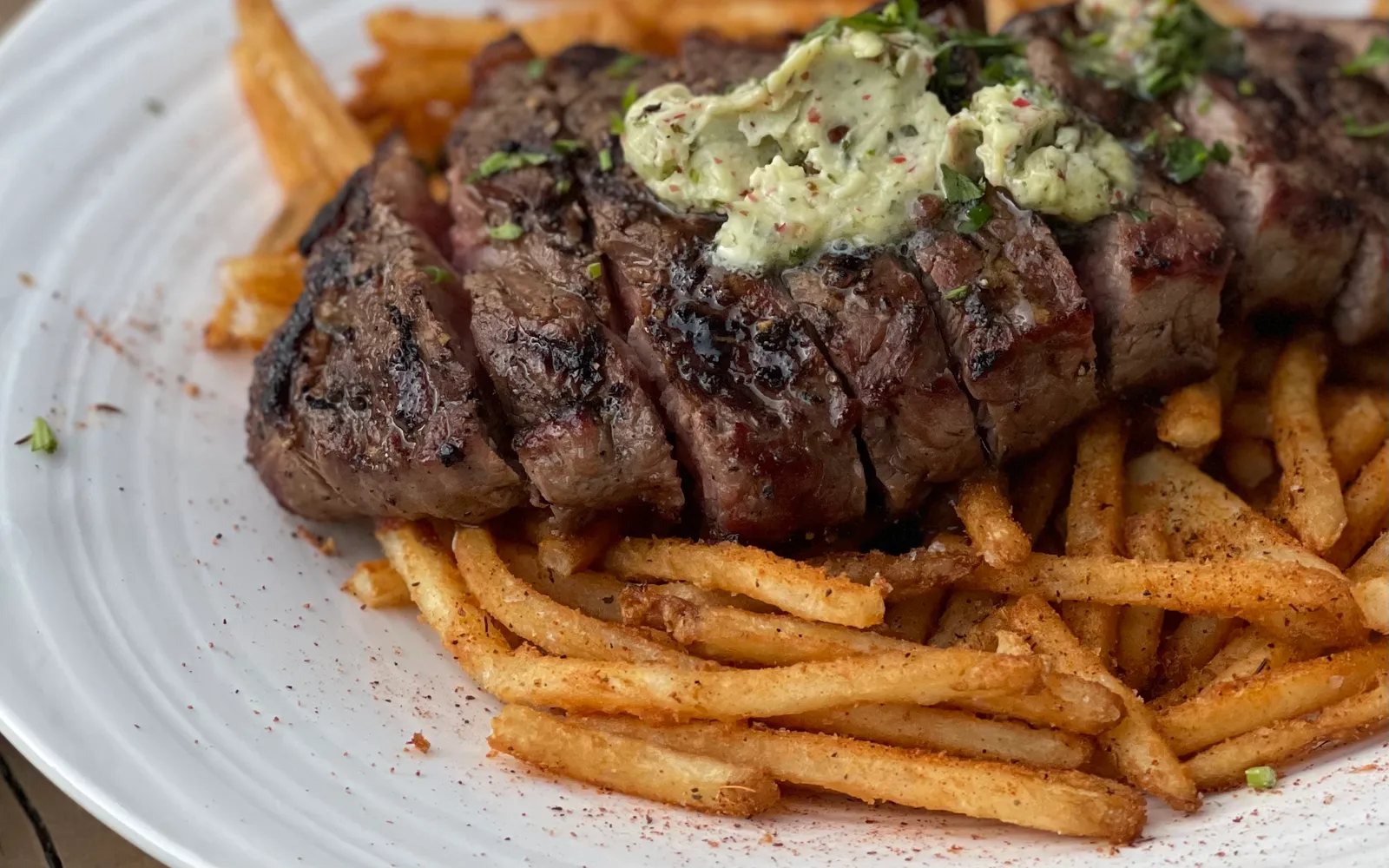 สเต็กเอนเทรโกตสไตล์บอร์โดบนจานขาวใบใหญ่ เนื้อ medium-rare หั่นบางสีชมพู ราดซอสบอร์เดอแลสีน้ำตาลเข้มมันเงา โรยหอมแดงและผักชีฝรั่ง