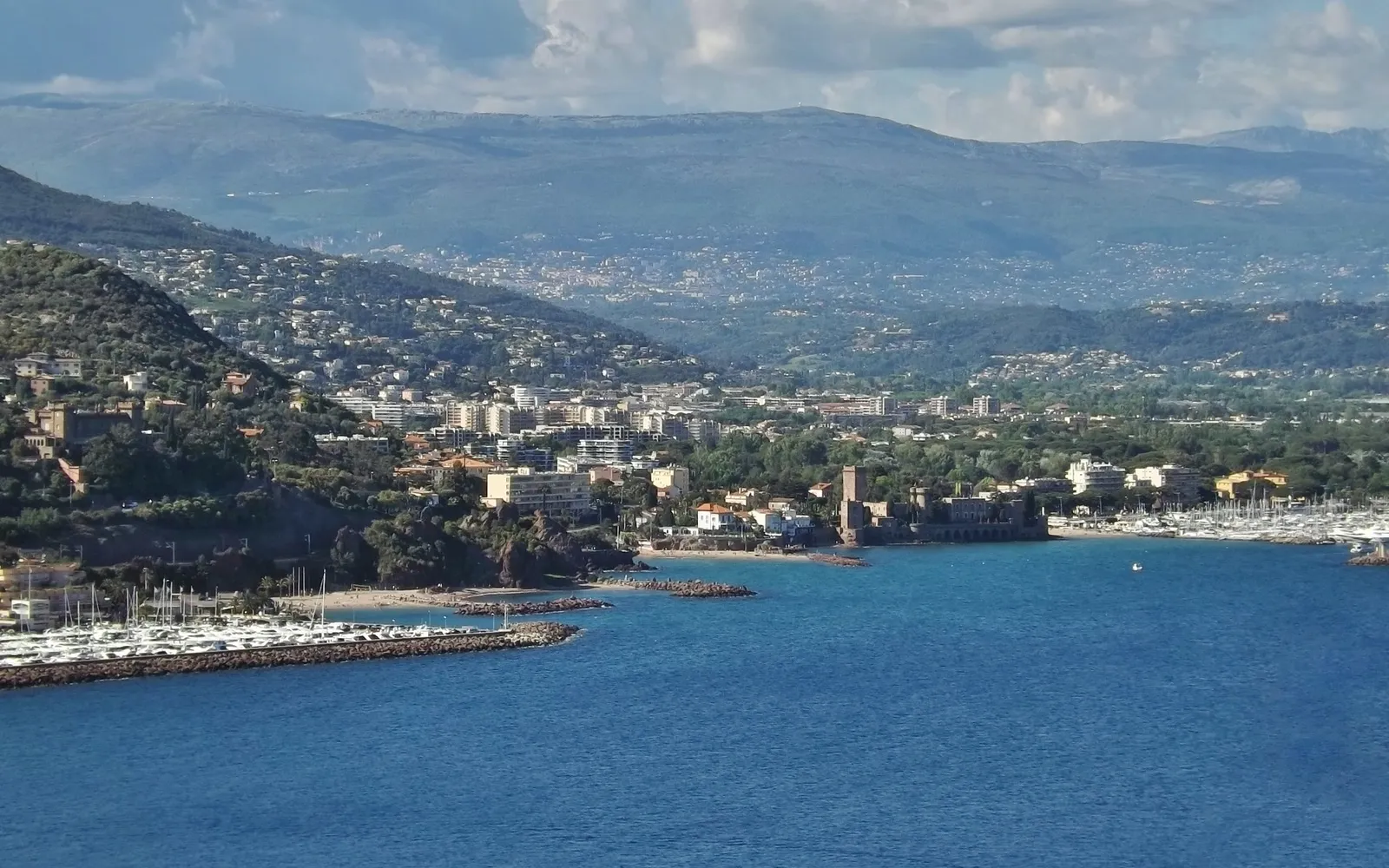 อ่าวนาปูลและปราสาทโบราณ Château de la Napoule ริมทะเล ฉากหลังเป็นทิวเขา Esterel สีแดงส้มที่ตัดกับท้องฟ้าน้ำเงินใส