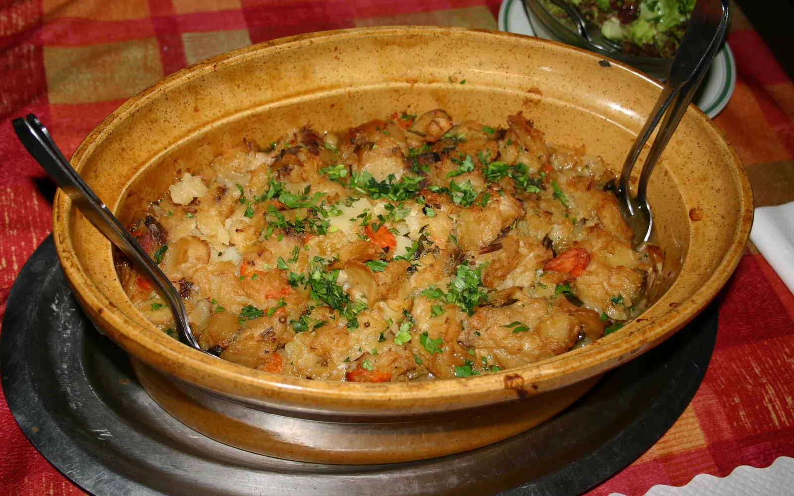 หม้อดินเผาฝาปิดสไตล์อัลซาสบนโต๊ะร้านอาหาร เปิดฝาออกให้เห็นเนื้อหมู เนื้อแกะ และเนื้อวัวตุ๋นกับผักและไวน์ไรสลิง
