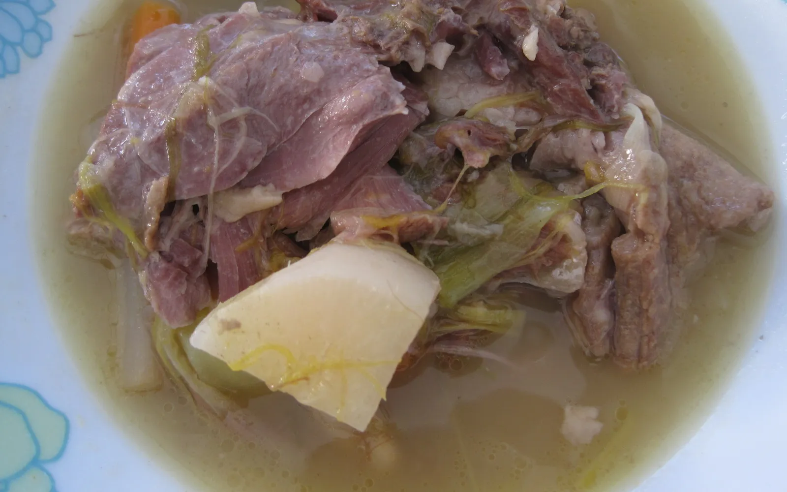 ซุป Garbure ในหม้อดินเผาบนโต๊ะ เนื้อเป็ด confit ขาใหญ่โผล่พ้นซุปกะหล่ำปลีและผักรากสีเขียวเข้ม ไอควันร้อนกรุ่น