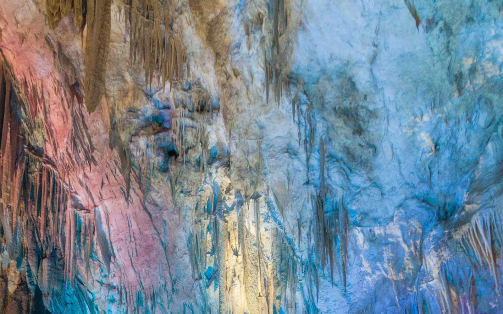 ภายในถ้ำโพรมีธีอุส หินงอกหินย้อยใต้แสงไฟสีฟ้าและส้มสร้างทิวทัศน์เหมือนดินแดนแฟนตาซี สระน้ำใสสะท้อนเพดานถ้ำ
