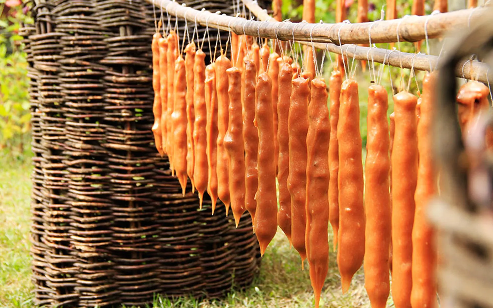 Churchkhela ห้อยเป็นพวงหลากสีในร้านขนมมตสเคตา สีน้ำตาลแดงและม่วงของน้ำองุ่นเข้มข้นเคลือบเมล็ดวอลนัทเรียงเป็นเส้น