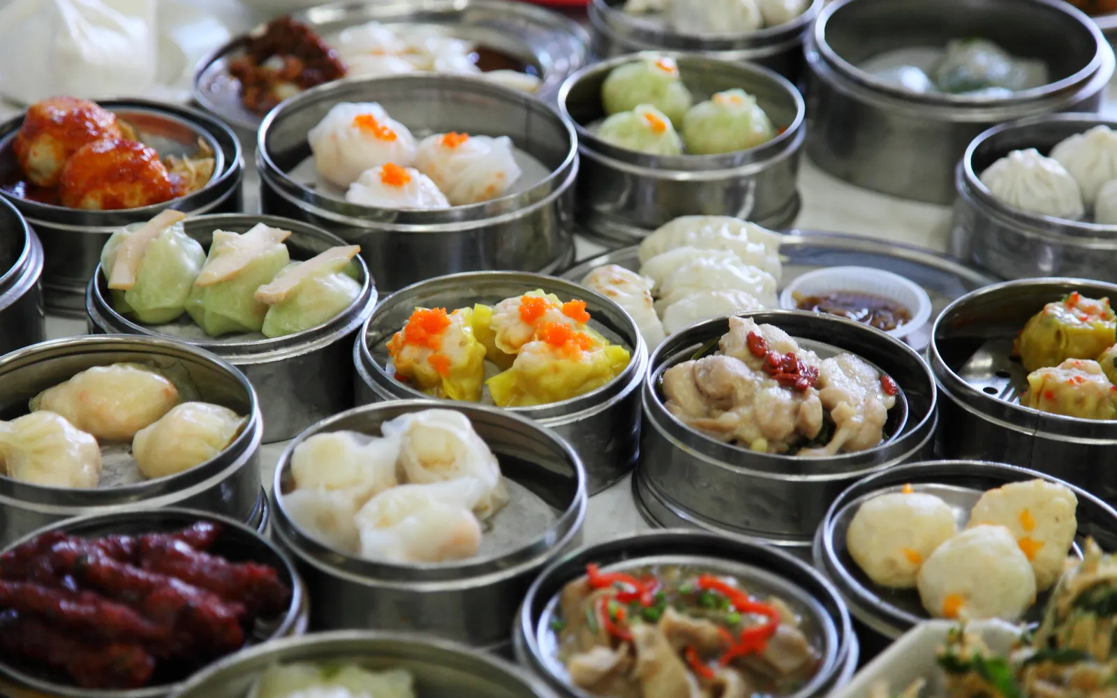 ถาดไม้ไผ่ติ่มซำฮ่องกง ฮาเกา ซิวไม และชาชงร้อนบนโต๊ะผ้าขาว