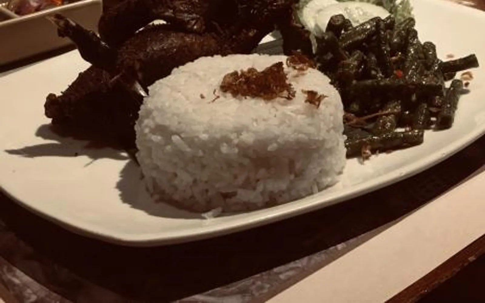 อะยัม เบตูตู บาหลี ไก่ทั้งตัวสีน้ำตาลเข้มห่อใบตองเสิร์ฟบนถาดไม้ พร้อมซัมบัลและข้าวสวย