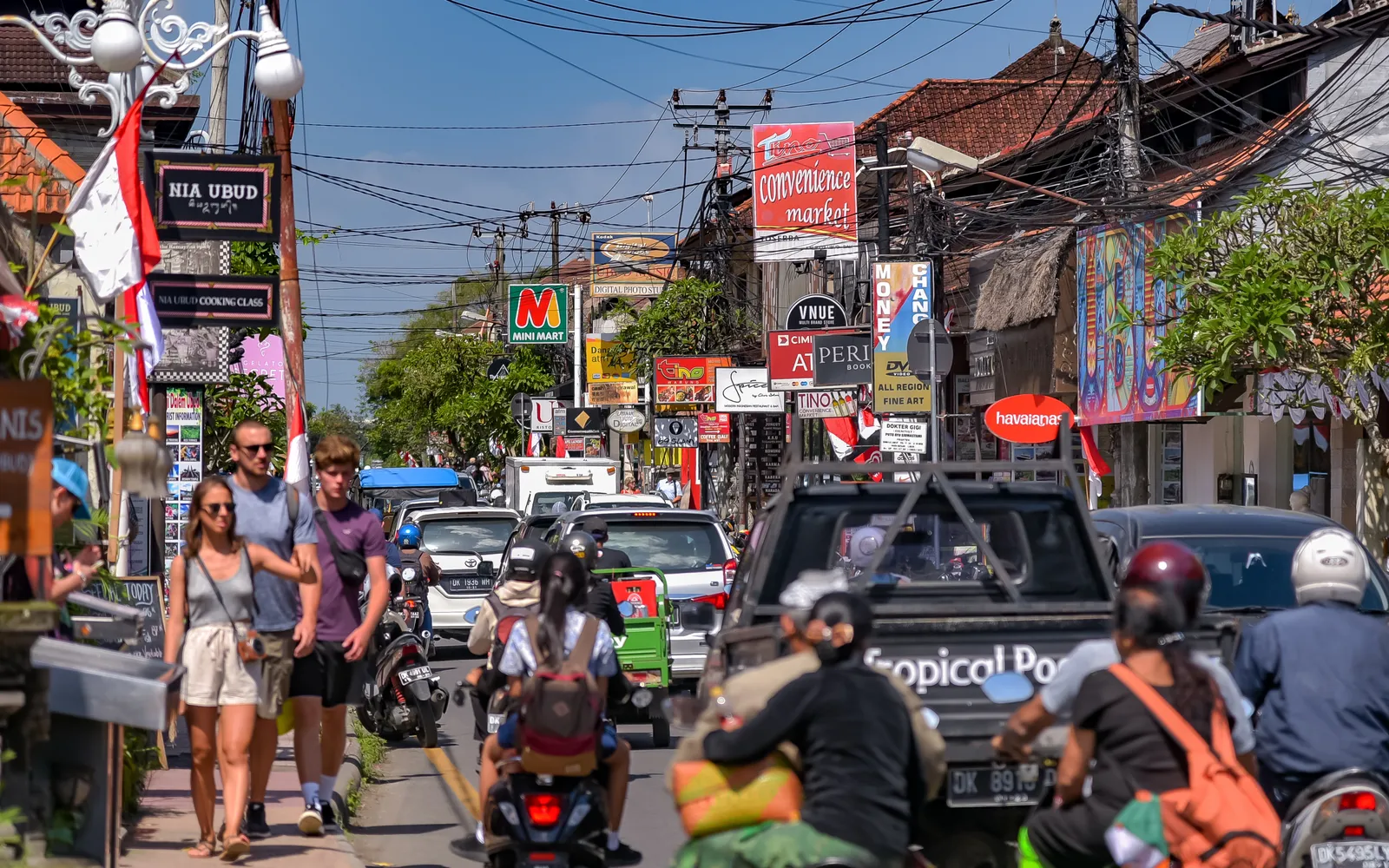 แผงขายผ้าบาติกสีสันและงานแกะสลักไม้ในตลาดศิลปะอูบุด บาหลี ผู้คนเดินเลือกซื้อของที่ระลึก