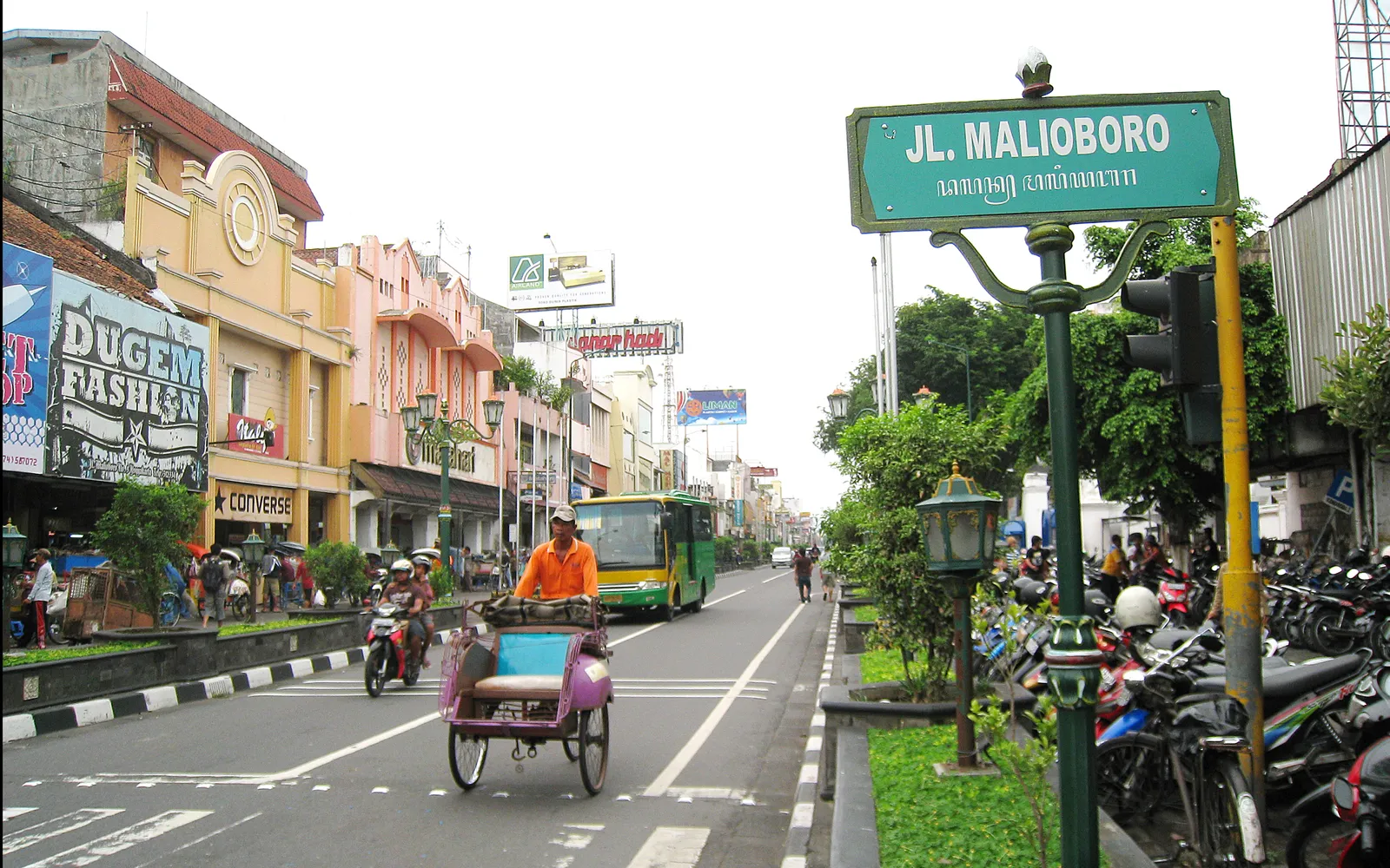 ถนนมาลีโอโบโรยามค่ำ แสงไฟสีส้มสาดส่องแผงขายของและร้านค้าสองฝั่งถนน