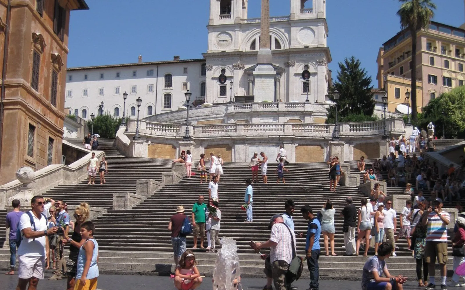 บันไดสเปนโรม 135 ขั้นสีหินทรายไล่ขึ้นสู่โบสถ์ Trinità dei Monti ด้านล่างน้ำพุเรือหักและนักท่องเที่ยวนั่งพักเต็มขั้นบันได