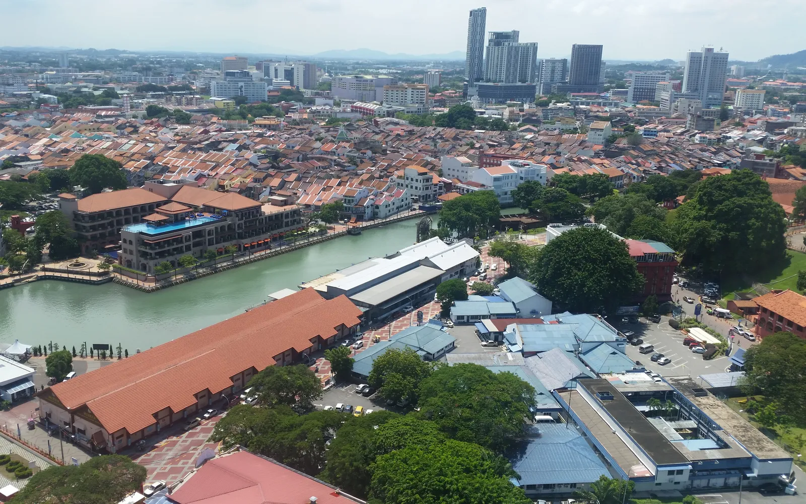 A boat on the Melaka River passing colonial-era houses and riverside murals at night
