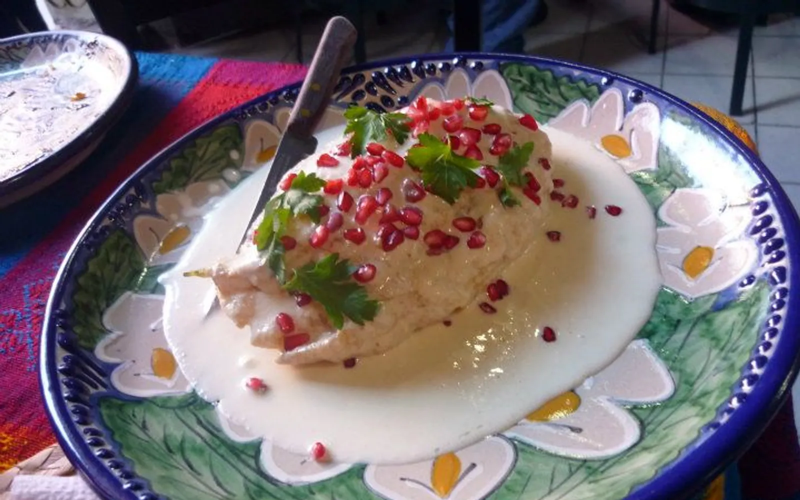 พริก Poblano สอดไส้เนื้อสับราดซอสวอลนัทสีขาวโรยทับทิมและผักชีสีสันธงชาติเม็กซิโก