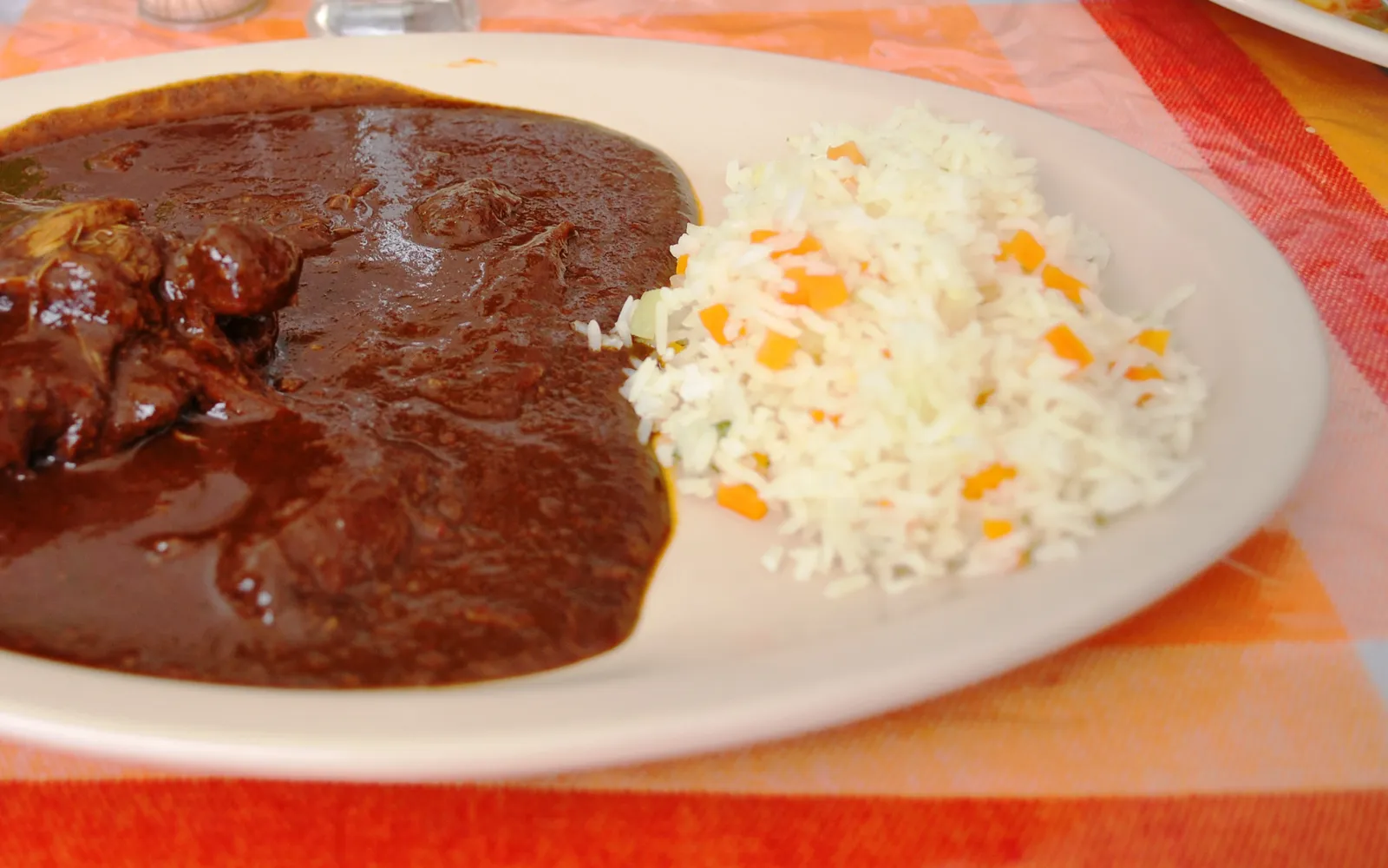 ไก่ราดซอสโมเลสีดำเข้มเสิร์ฟพร้อมข้าว Arroz และถั่ว Frijoles