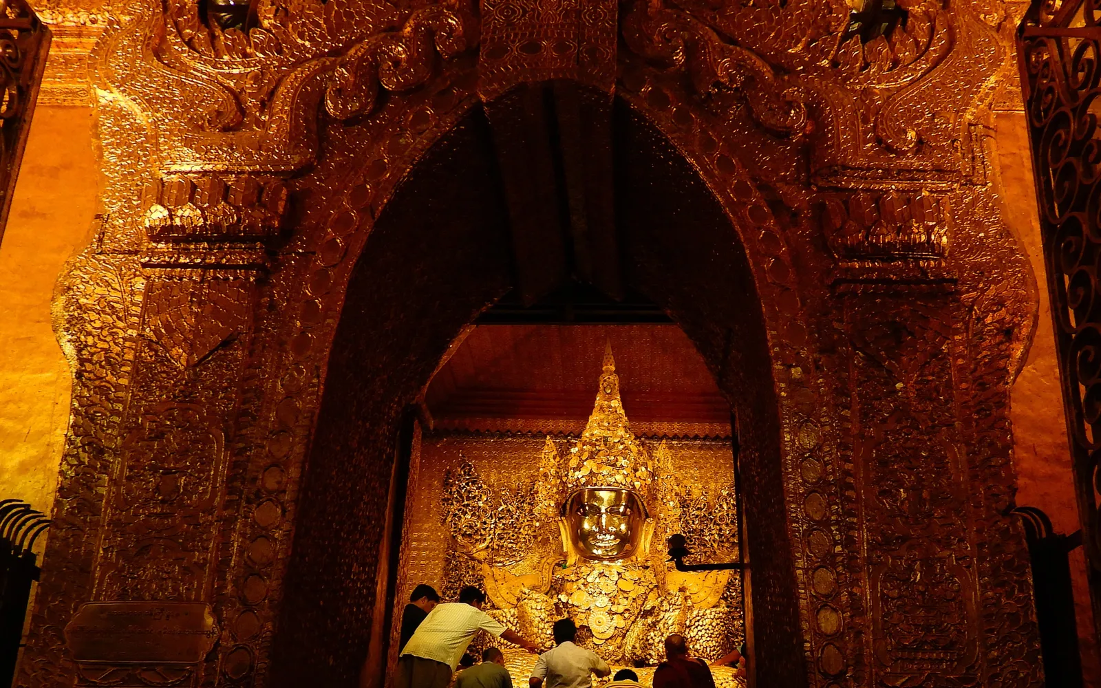 ช่างแกะสลักไม้ในย่านหัตถกรรมมัณฑะเลย์ มือชำนาญเจาะลวดลายพระพุทธรูปจากท่อนไม้สักในโรงงานเปิดโล่งริมถนน