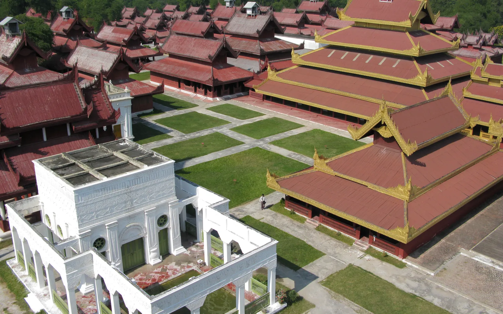 พระราชวังมัณฑะเลย์กลางกำแพงสีขาวล้อมคูน้ำสี่เหลี่ยมขนาดใหญ่ หอคอยทองสูงเด่นตัดกับท้องฟ้าสีฟ้า