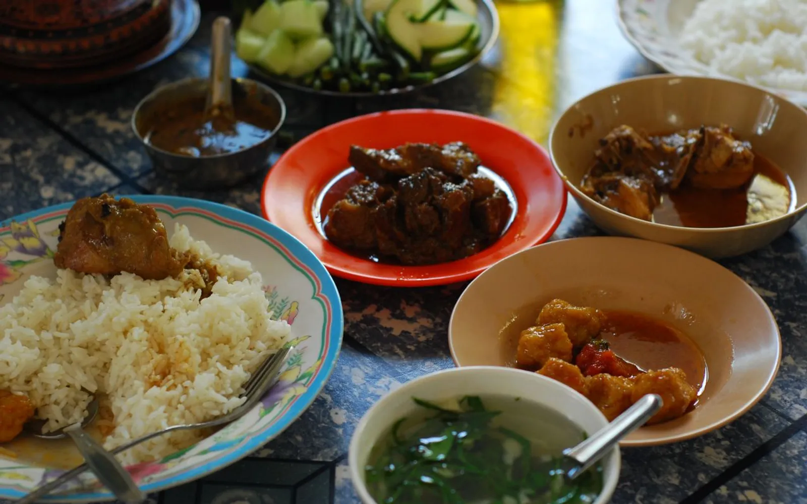 แกงปลาพม่าในกระทะดินเผา เนื้อปลาชิ้นโตในน้ำแกงสีส้มแดงหอมขมิ้น ผักชีและพริกสดวางประดับบนหน้าแกง