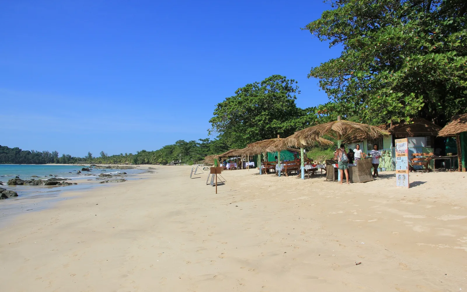 มุมสูงจากเนินเขาเหนือหาดงาปาลีมองลงมาเห็นแนวชายหาดทรายขาวโค้งยาวริมอ่าวเบงกอล น้ำทะเลสีฟ้าครามตัดกับทรายขาวและป่าต้นมะพร้าวสีเขียว