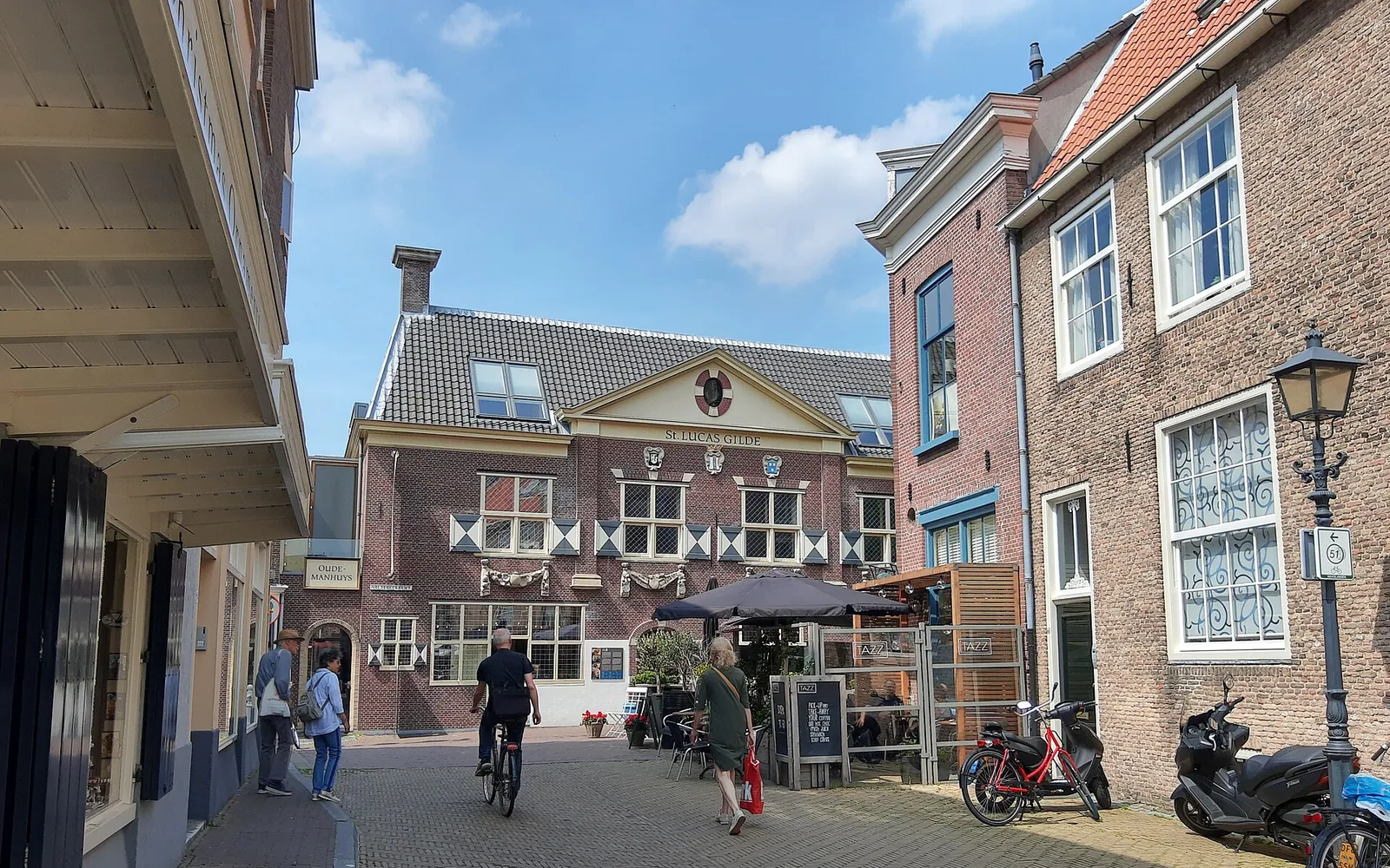 ด้านหน้าอาคาร Vermeer Centrum Delft ป้ายชื่อสีน้ำเงินขาวตามสไตล์เดลฟต์แท้ ถนนหินกรวดเก่าหน้าทางเข้า