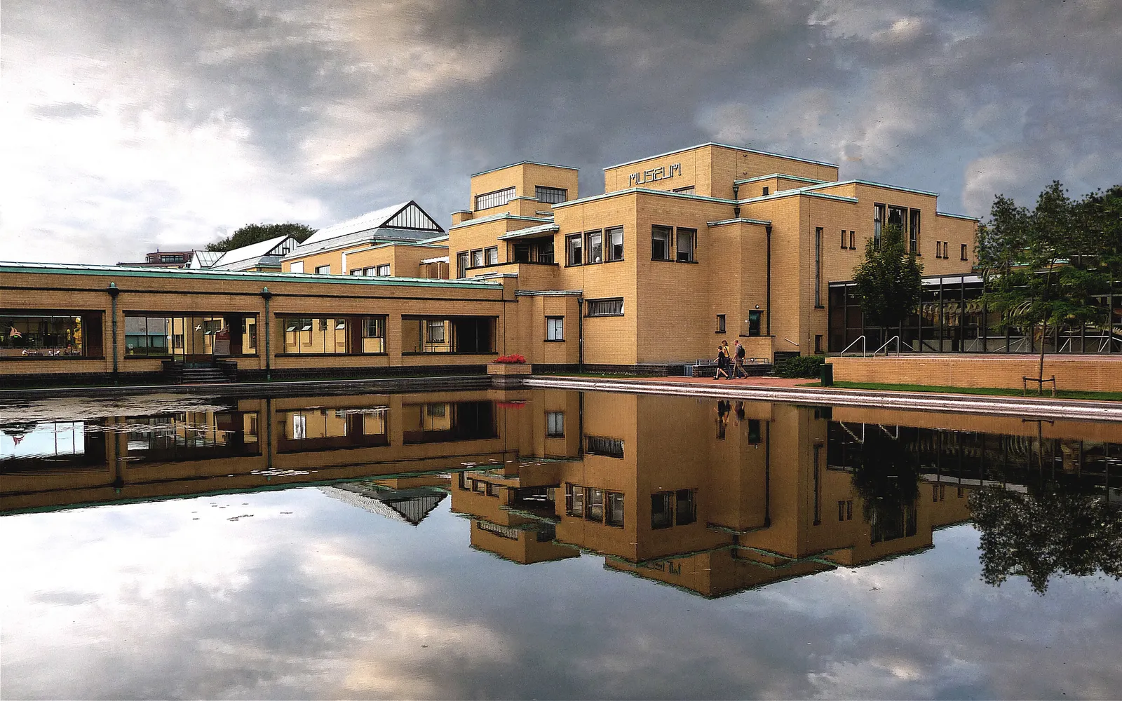 อาคาร Kunstmuseum Den Haag สไตล์ Amsterdam School อิฐเหลืองอบอุ่น สะท้อนกระจกน้ำในสระด้านหน้า