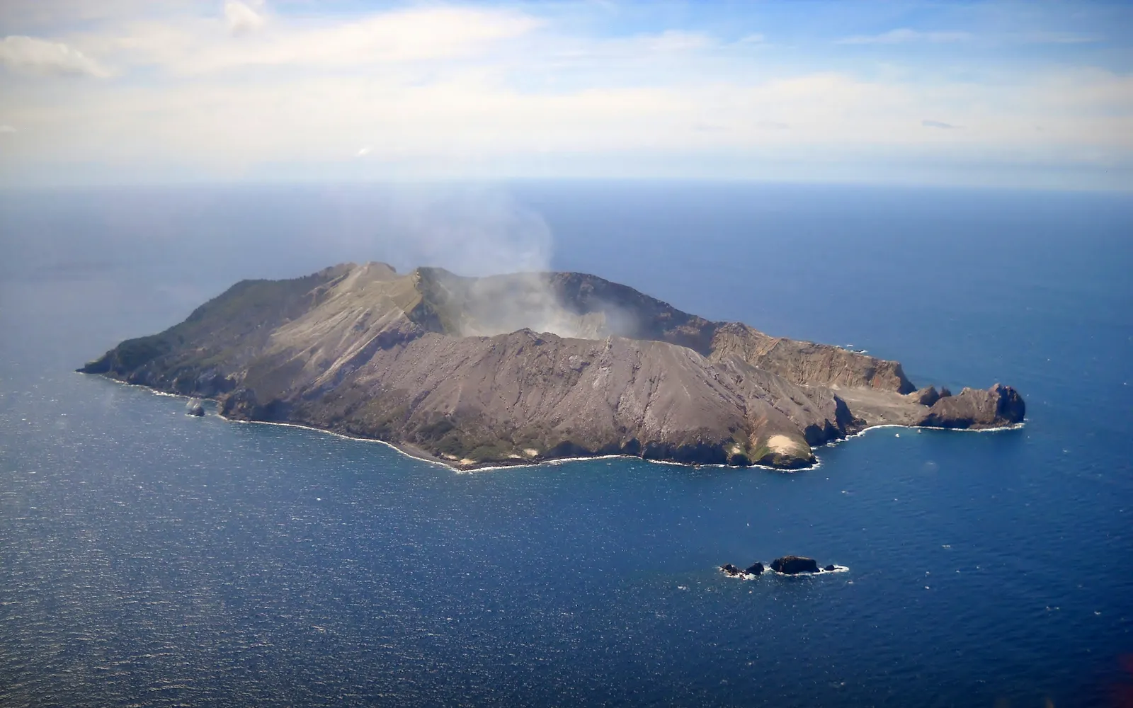 เกาะ White Island ภูเขาไฟที่ยังคุกรุ่น ควันสีขาวพุ่งขึ้นจากยอดเขาเหนือผิวมหาสมุทรสีน้ำเงินเข้ม