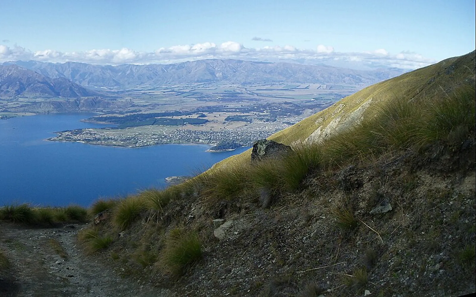 สันเขา Roys Peak มองลงเห็นทะเลสาบวานากาสีครามระหว่างเทือกเขาหิมะ ทางเดินแคบๆ ไต่ขึ้นไปตามสันเขา