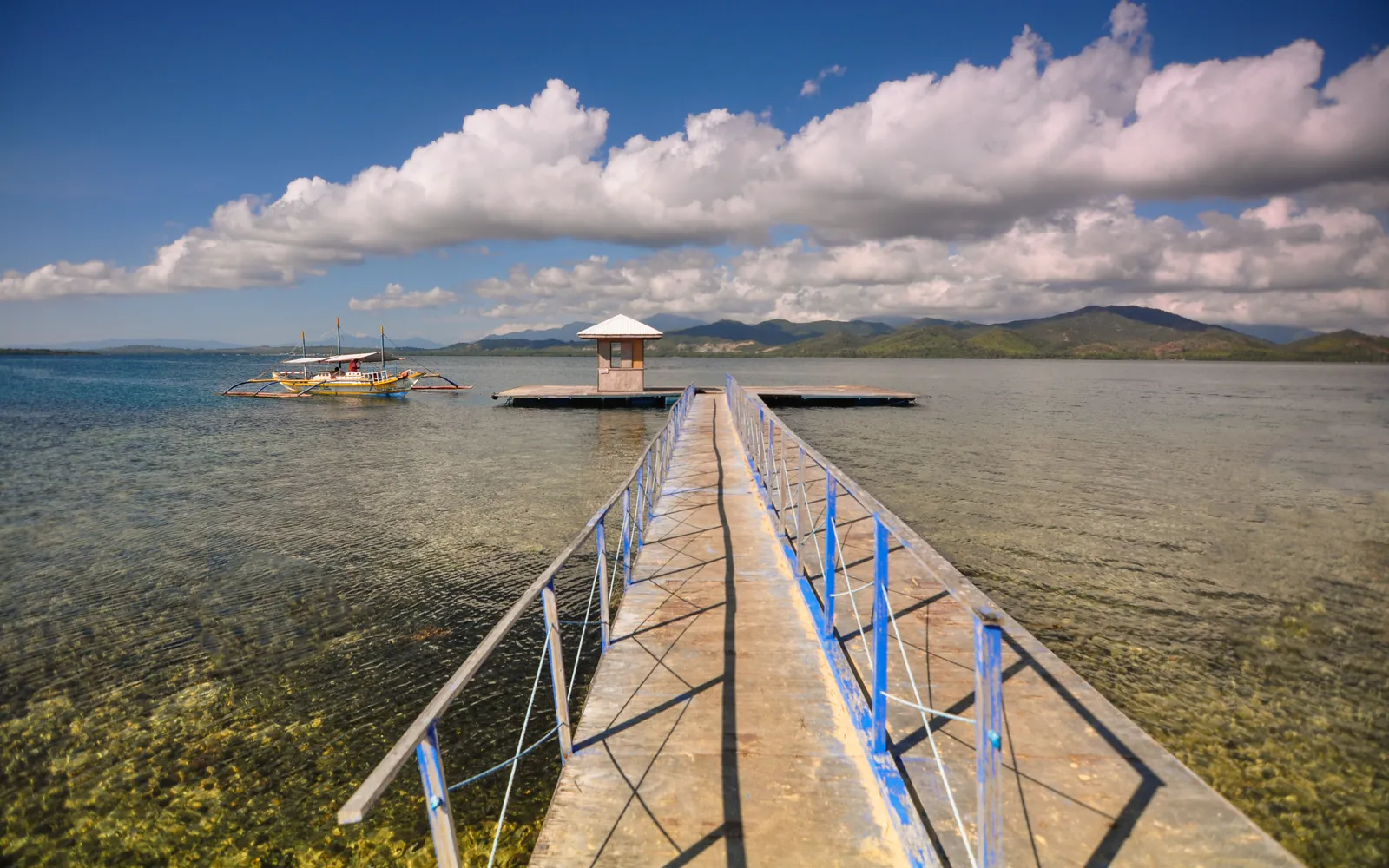เรือล่องผ่านเกาะเล็กน้อยในฮอนดาเบย์ น้ำทะเลสีเขียวใส