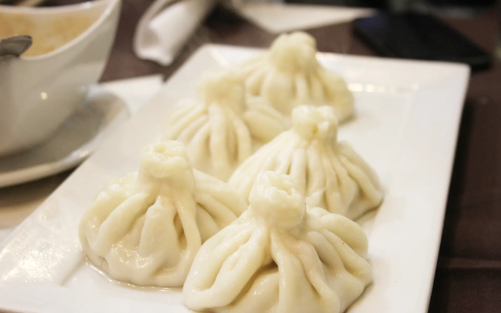 ชินคาลีเกี๊ยวจอร์เจียทรงลูกแพร์ขนาดใหญ่นึ่งสุก เรียงบนจาน ด้านบนเป็นปมแป้งบิดๆ โรยพริกดำหยาบ