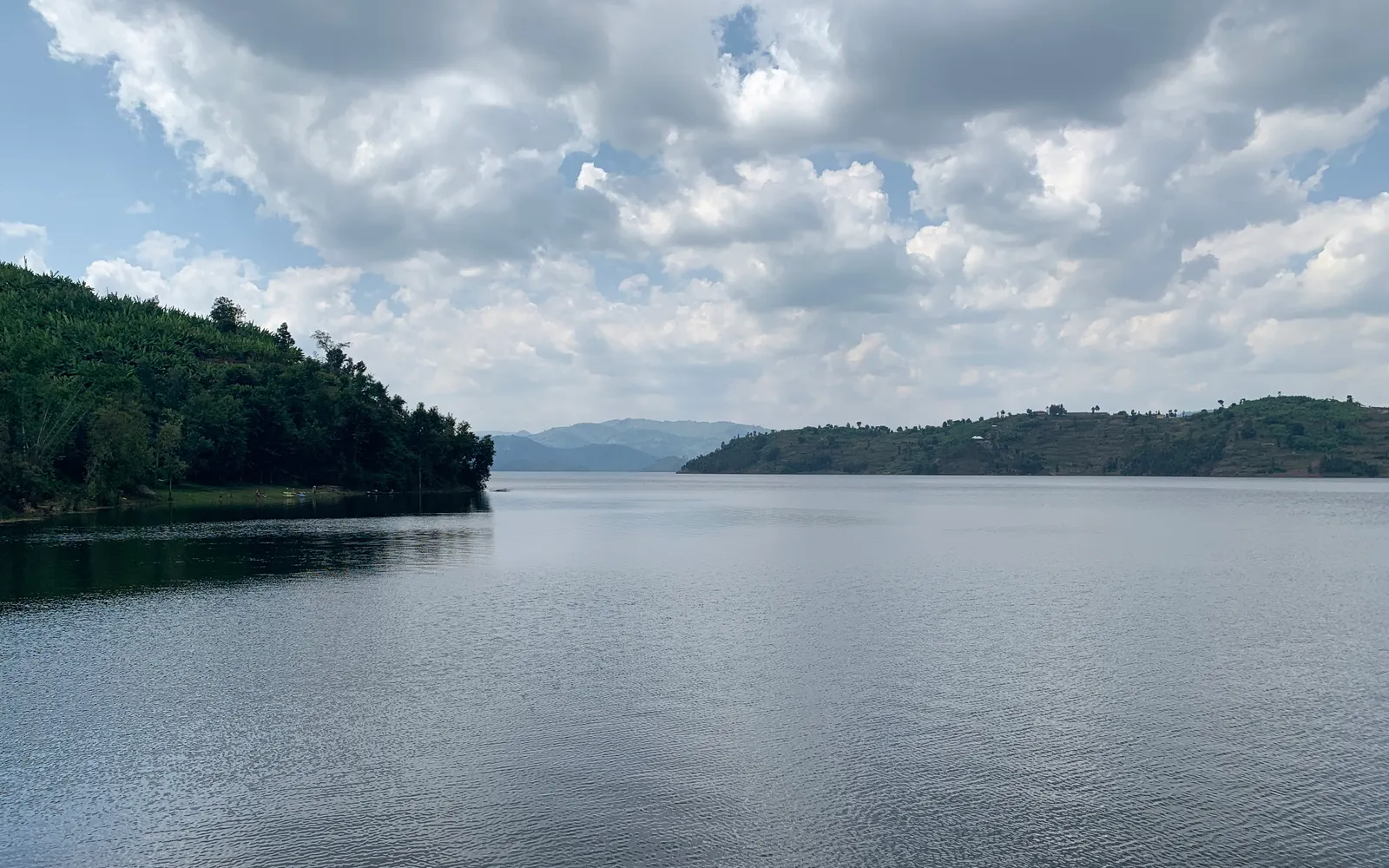 ทะเลสาบบูเรราน้ำใสกับฉากหลังภูเขาไฟ Virunga และเนินเขาเขียว