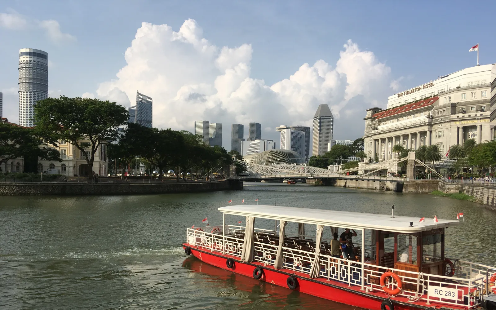 เรือบัมโบ๊ตไฟฟ้าล่องบนแม่น้ำสิงคโปร์ยามค่ำคืนพร้อมแสงไฟสะท้อนน้ำ