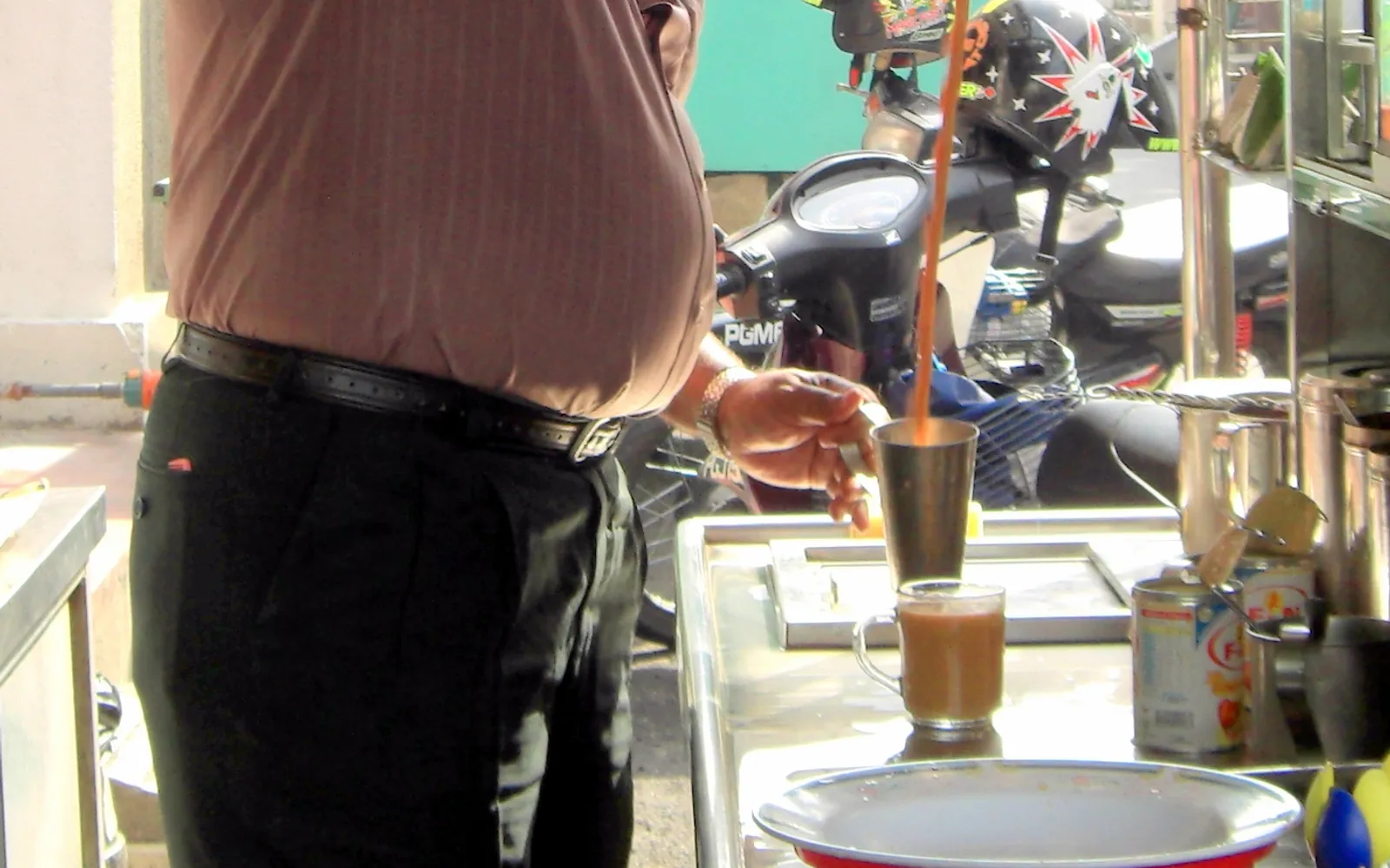 แก้วเต๋ห์ตาริกที่มีฟองนมสีขาวฟูด้านบน บนโต๊ะไม้ในร้านกาแฟแบบดั้งเดิม