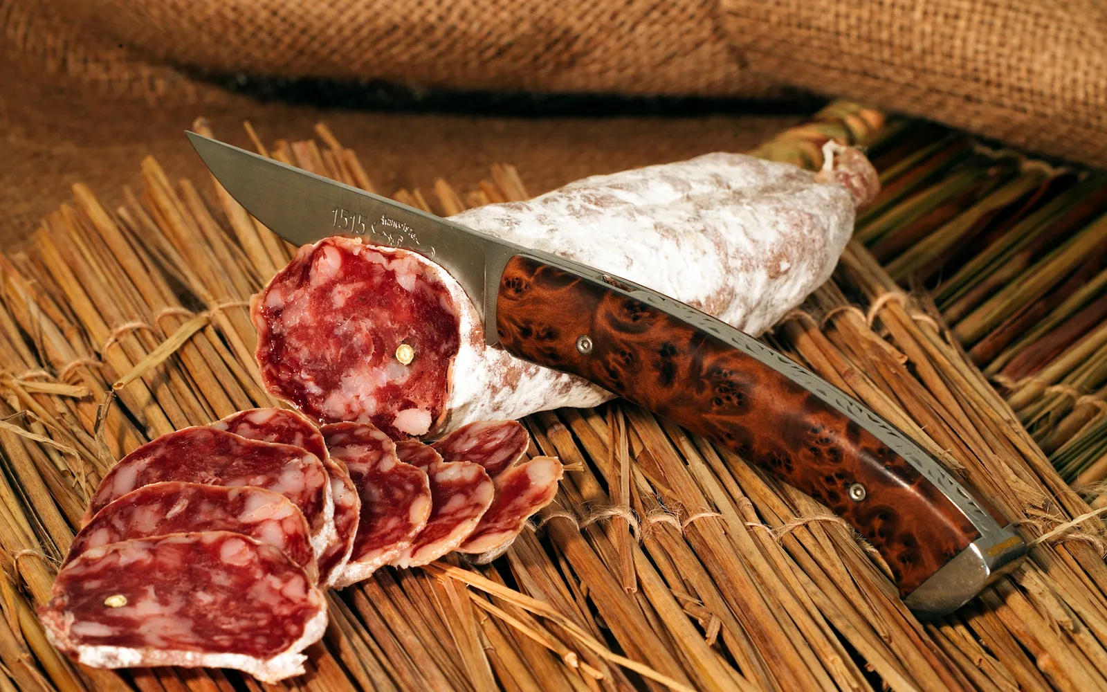ไส้กรอก Saucisson vaudois สีน้ำตาลแดงเข้มทั้งเส้น วางบนเขียงไม้พร้อมมีดหั่น ผิวเปลือกย่นเล็กน้อยสัญลักษณ์ของการรมควันแท้