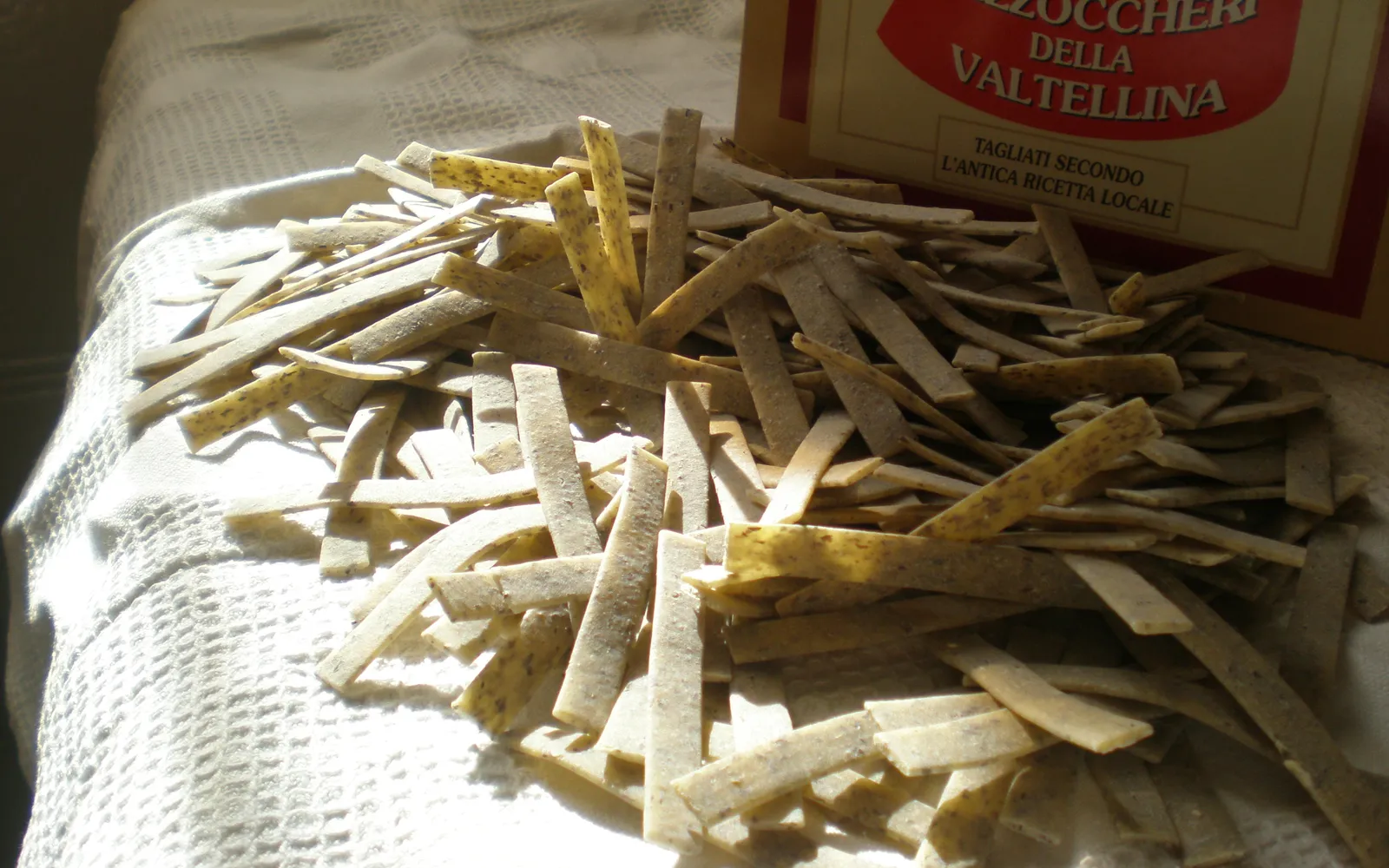 Pizzoccheri เส้นมักกะโรนีบัควีทสีน้ำตาลเทาผัดกับผักหัวกาดขาว มันฝรั่ง และชีส Valtellina Casera ละลายคลุกเคล้าบนจานร้อน