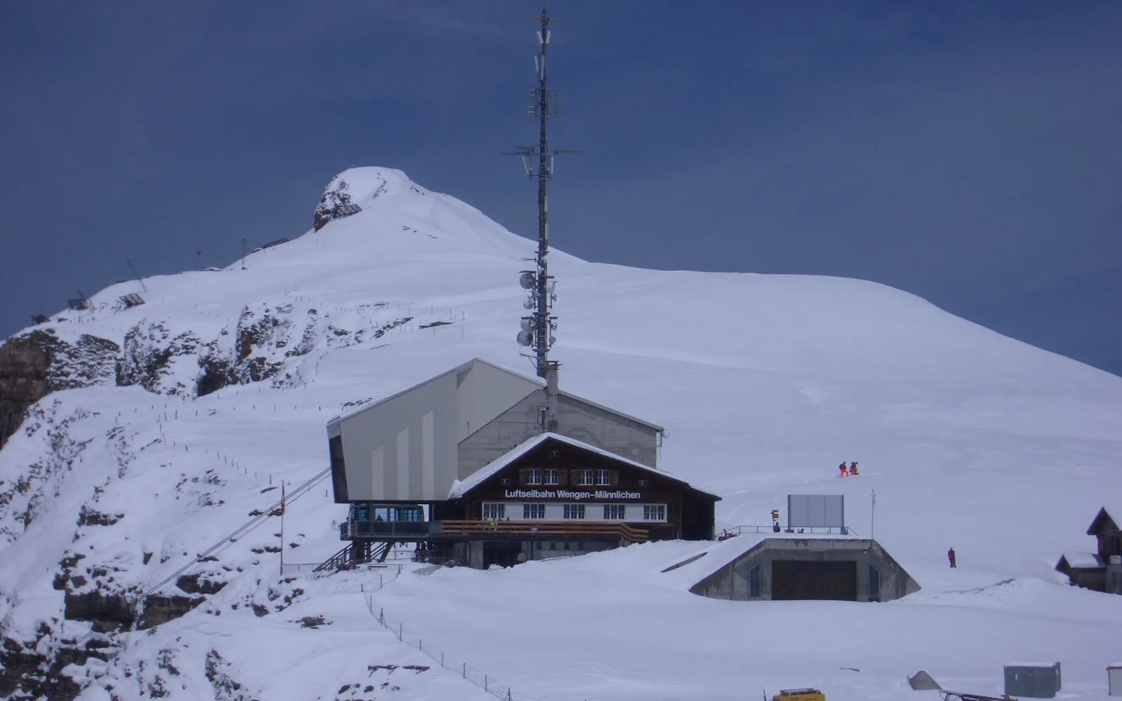 จุดชมวิวบนยอด Männlichen มองเห็นสามยอดใหญ่เรียงกันคือ Eiger มึนช์ และยุงเฟราว์ ทุ่งหญ้าเขียวในเบื้องหน้าและหมู่บ้านเล็กๆ ตัดกับหิมะขาว