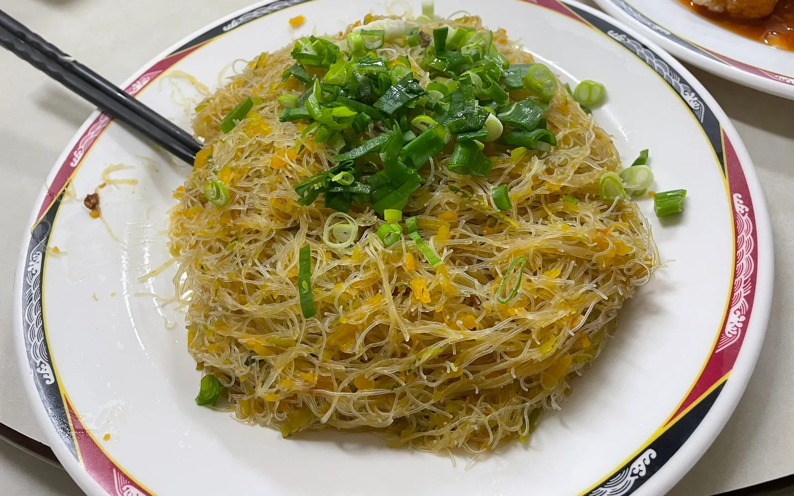 ชามหมี่เส้นสีเหลืองทองในน้ำซุปฟักทองข้นหอมหวานใส่ผักและเนื้อหมู