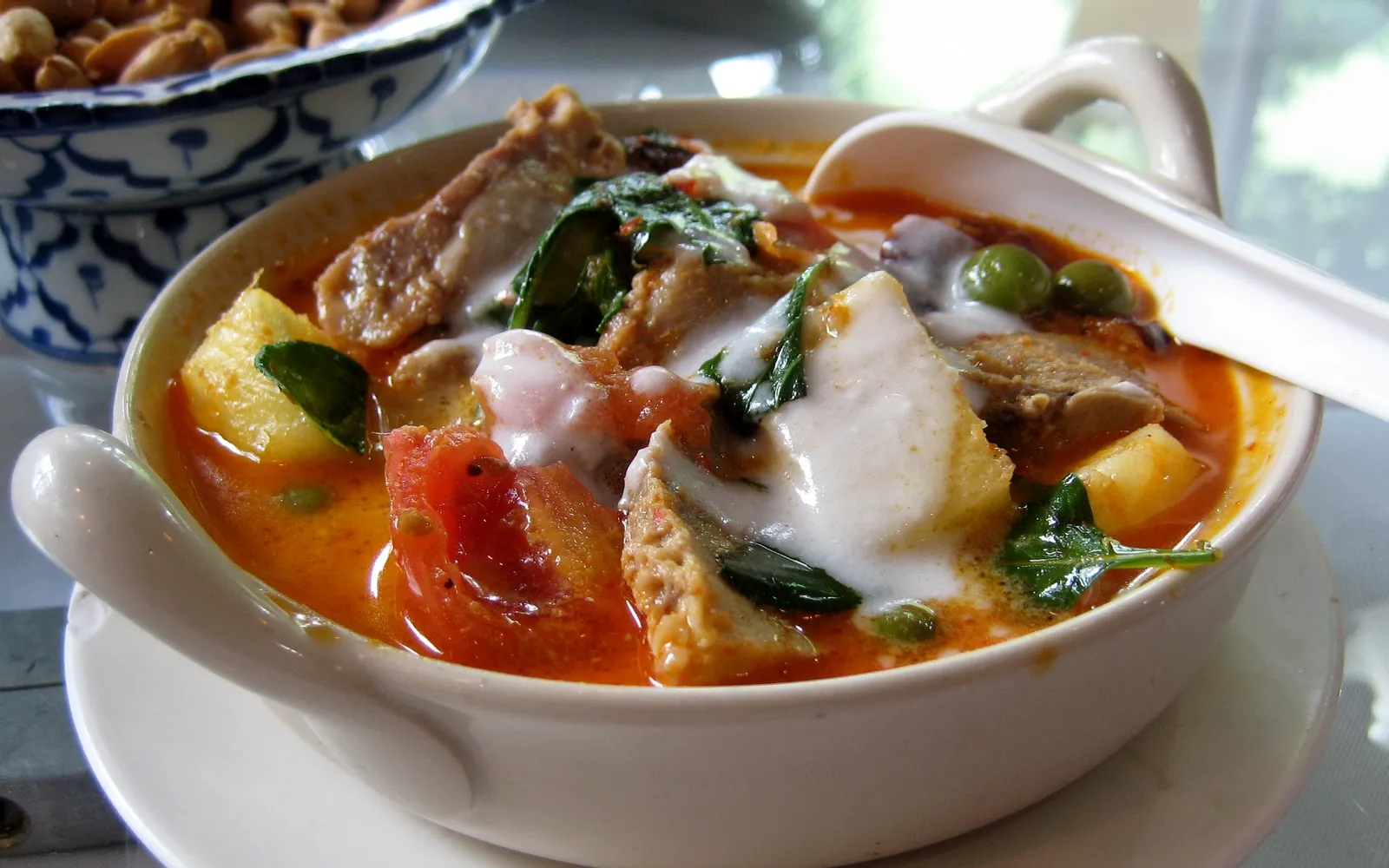 ข้าวแกงเขียวหวานไก่กะทิข้น ข้าวสวยร้อนในจานพร้อมแกงสีเขียวเข้มหอมสมุนไพรและมะเขือเทศ