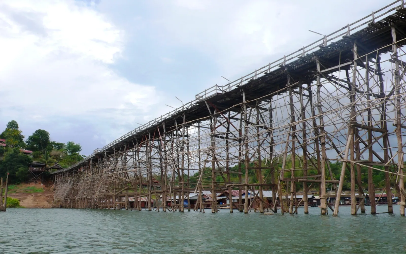 สะพานมอญไม้ยาวเหยียดพาดข้ามอ่างเก็บน้ำเขื่อนวชิราลงกรณ์ยามรุ่งอรุณ
