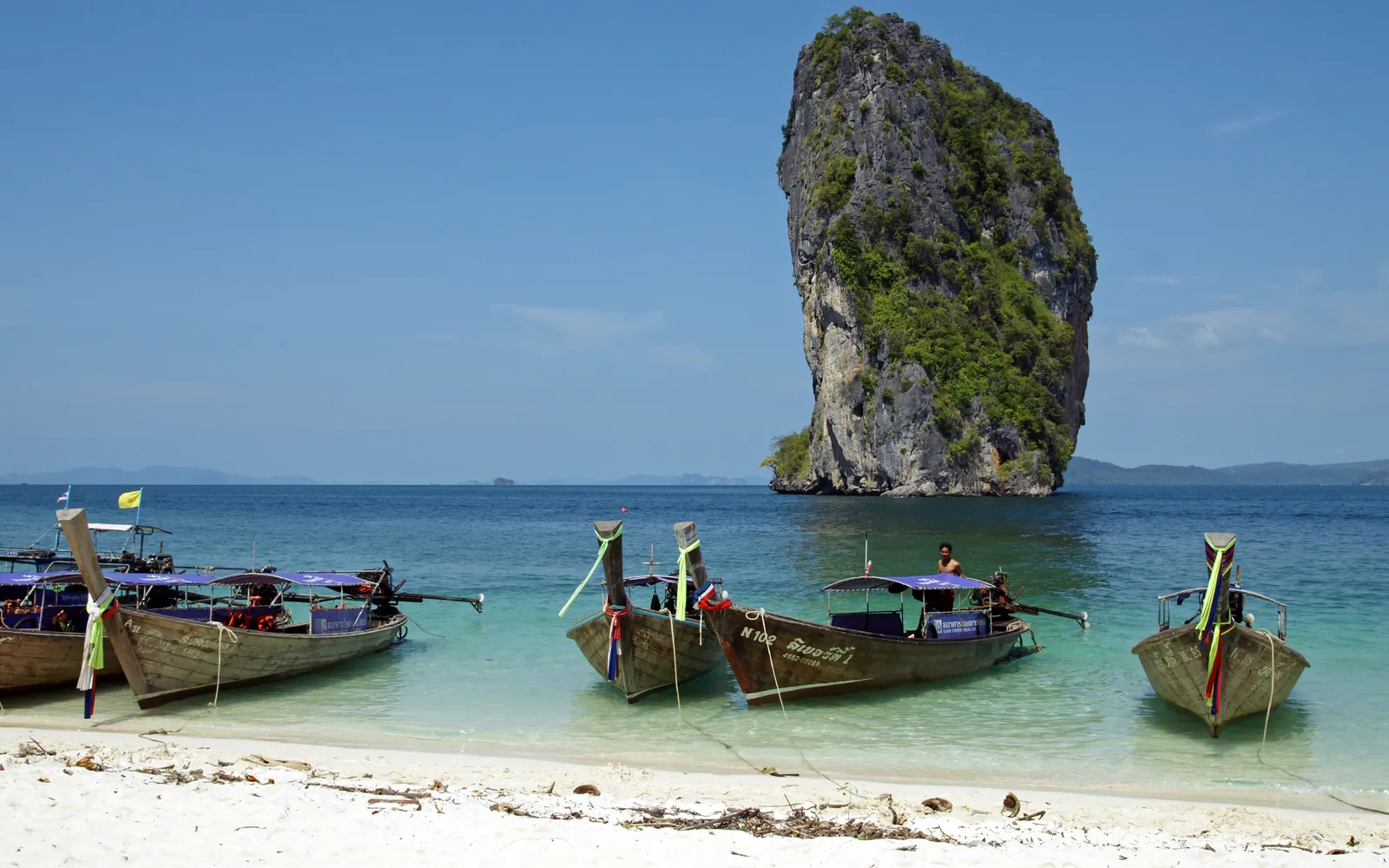 เกาะโพดาน้ำทะเลใสสีฟ้าคราม มีหินปูนโผล่เหนือน้ำ นักท่องเที่ยวดำน้ำตื้น