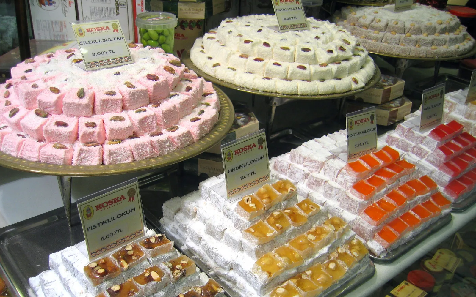 Turkish delight หลายสีเรียงในถาดไม้ สีชมพู เขียว ขาว และส้ม โรยผงน้ำตาลขาวด้านนอก แต่ละก้อนหน้าตาเรียบอวบ