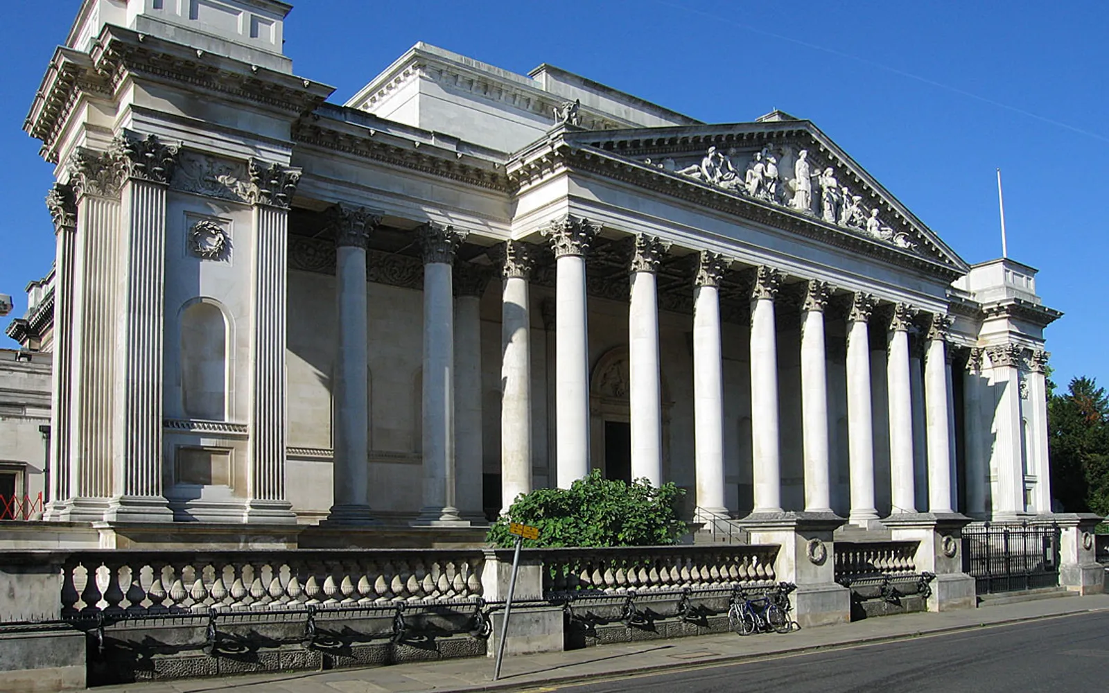 ทางเข้าพิพิธภัณฑ์ Fitzwilliam เคมบริดจ์ เสาหินโบราณสไตล์กรีกโรมันโอ่อ่าตระการตา บันไดหินกว้างนำขึ้นสู่ประตูใหญ่ที่มีนักท่องเที่ยวกำลังเดินเข้า
