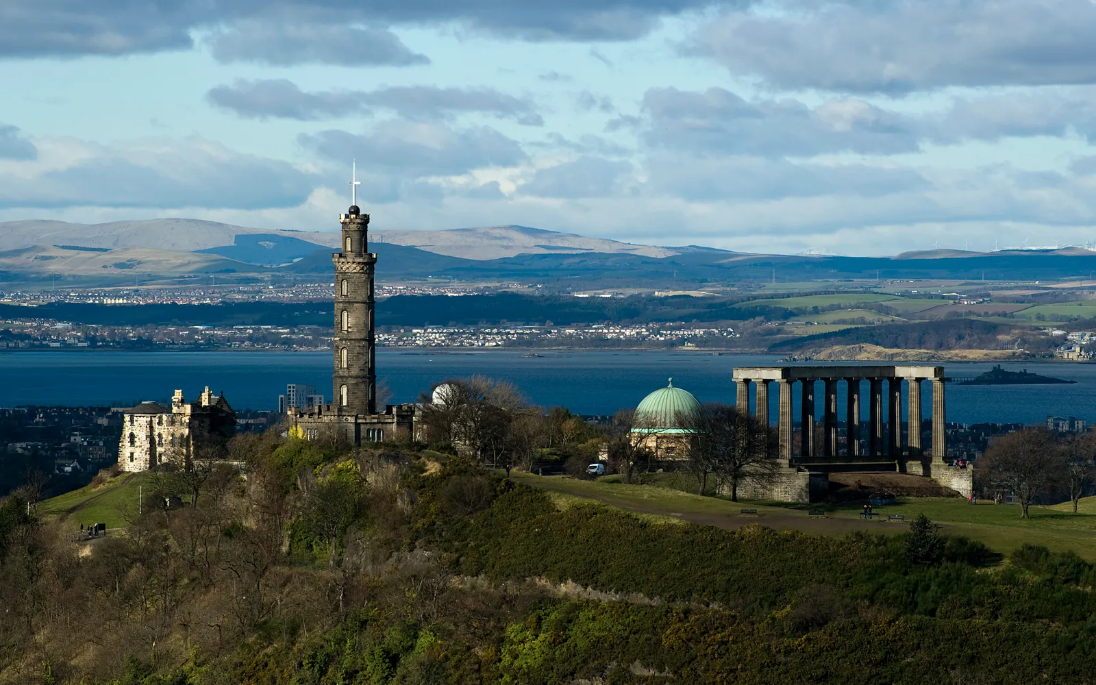 เนิน Calton Hill ในเอดินบะระ เสาหินแบบกรีกของ National Monument ตั้งตระหง่านบนยอดเนิน มองลงมาเห็นหลังคาเมืองเก่าและปราสาทในระยะไกล